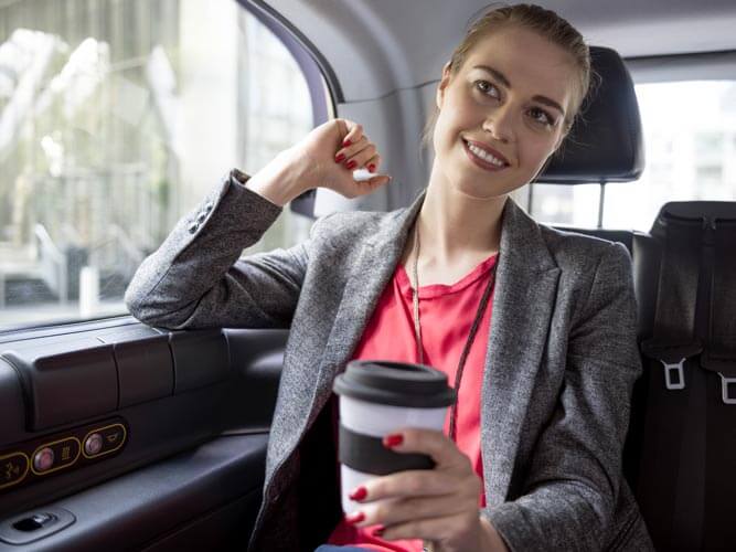 Business travel 2026: career woman in a car with a cup of cappuccino in her hand