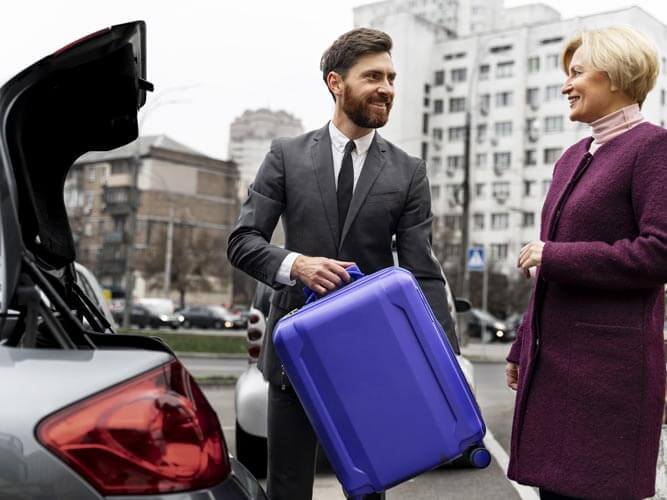 Business travel 2026: The driver helps the lady put her suitcase in the trunk