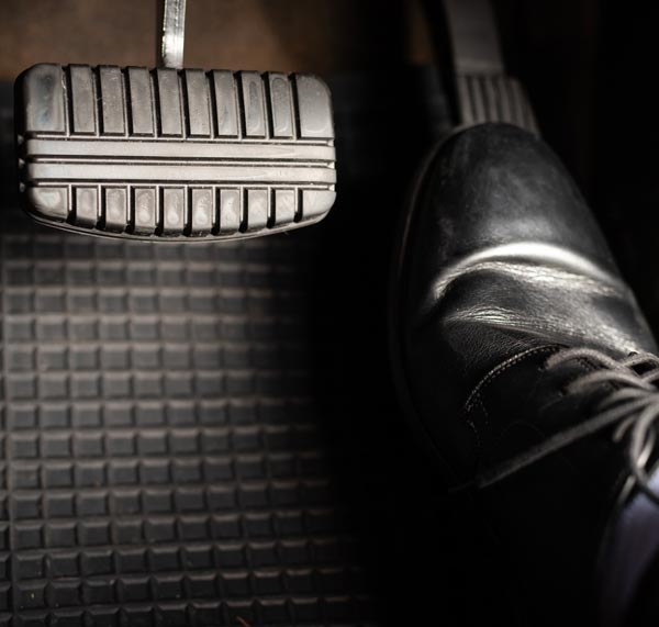 Chauffeur Service Milan: man leather shoes is stepping accelerator car